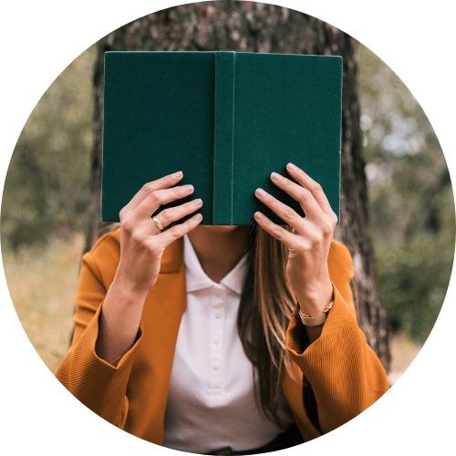 Donna vista di fonte legge seduta all'aperto con libro che copre il viso